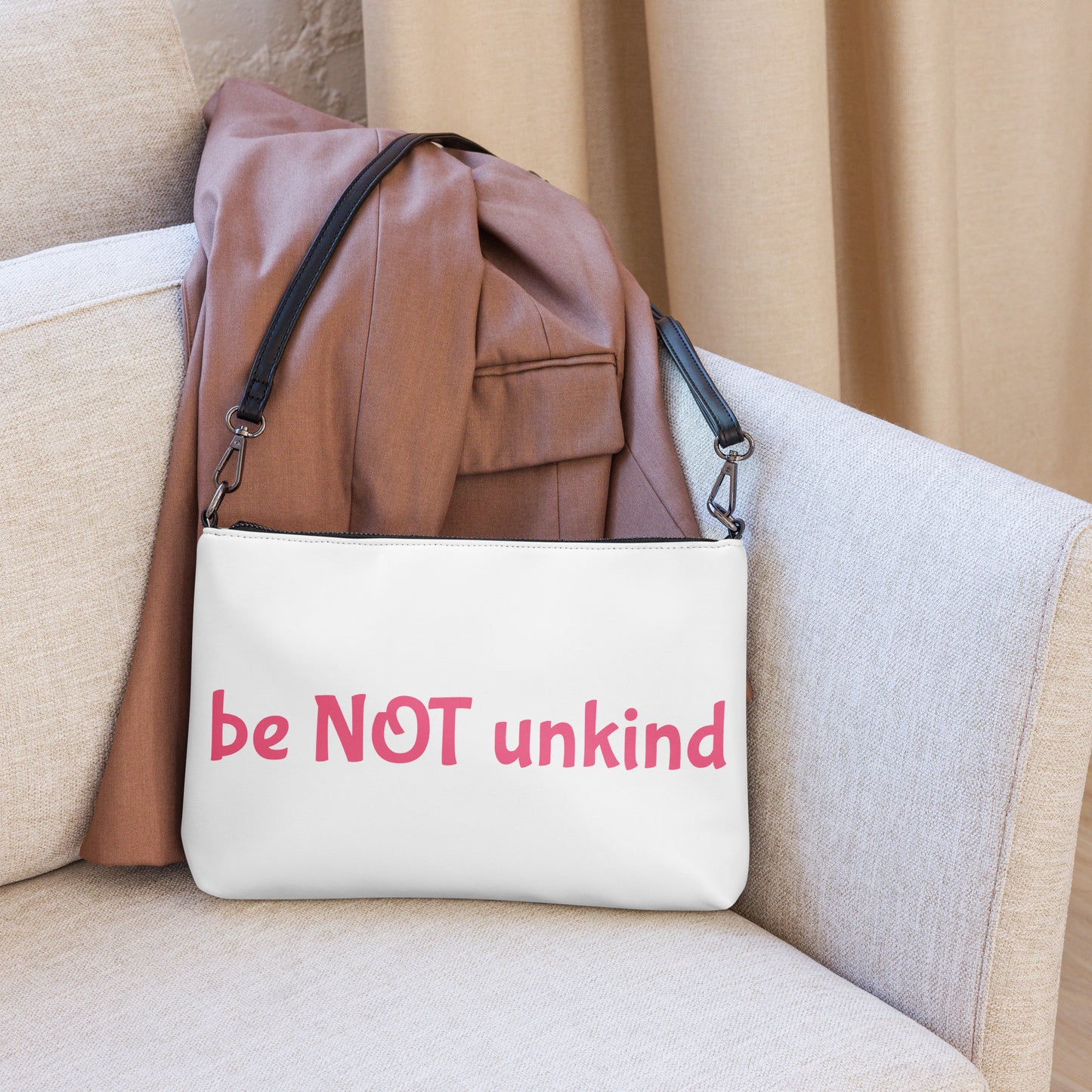 White bag with 'be NOT unkind' text on a beige couch
