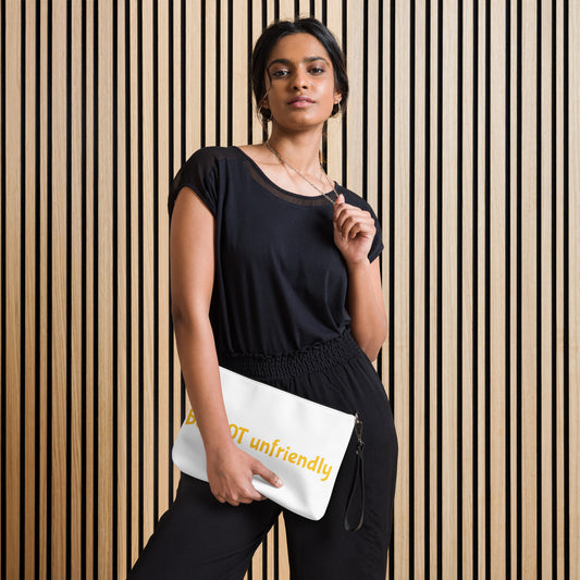 Woman holding a white clutch with 'be not unfriendly' text design against a striped wall.