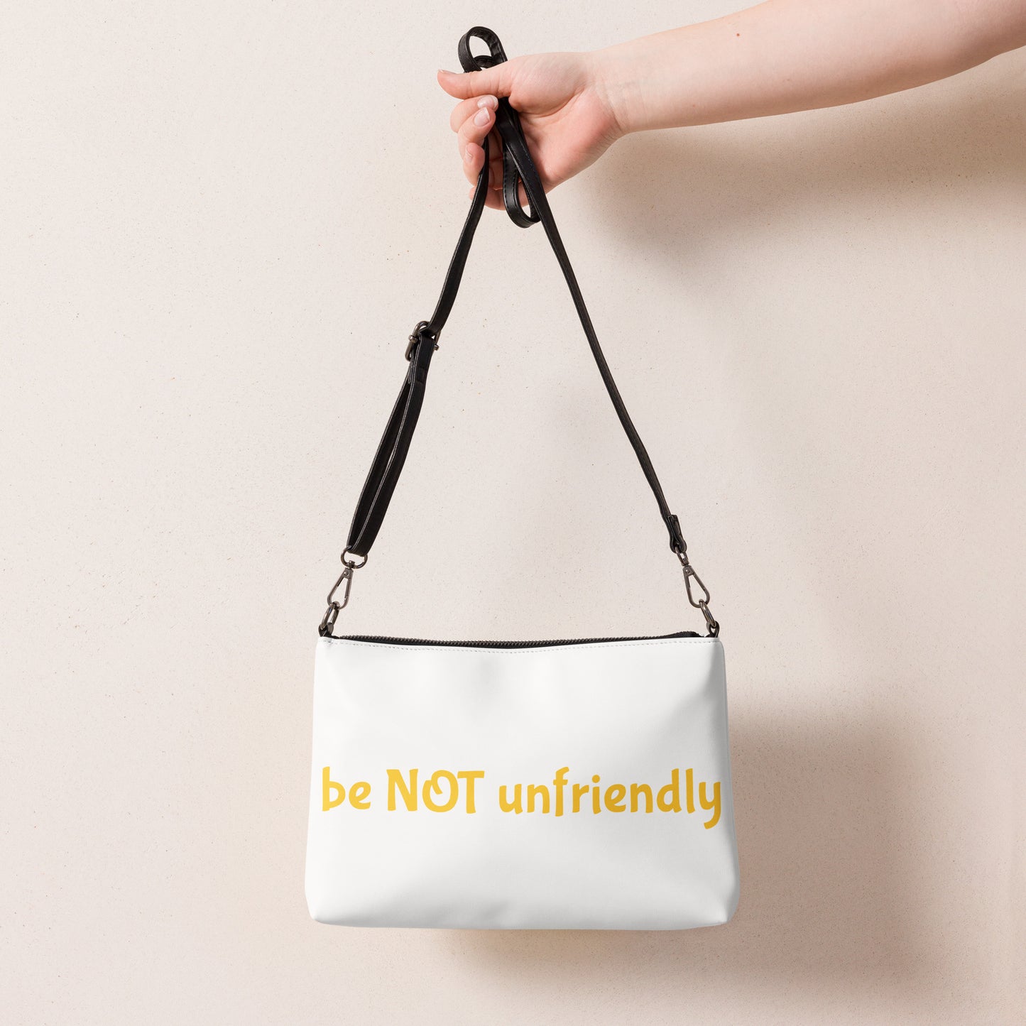 White bag with 'be NOT unfriendly' text held by a hand against a beige background