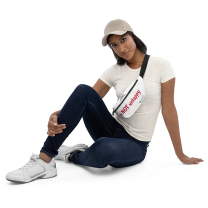 Woman sitting on the floor wearing a white t-shirt, blue jeans, and white sneakers, holding a white crossbody bag.