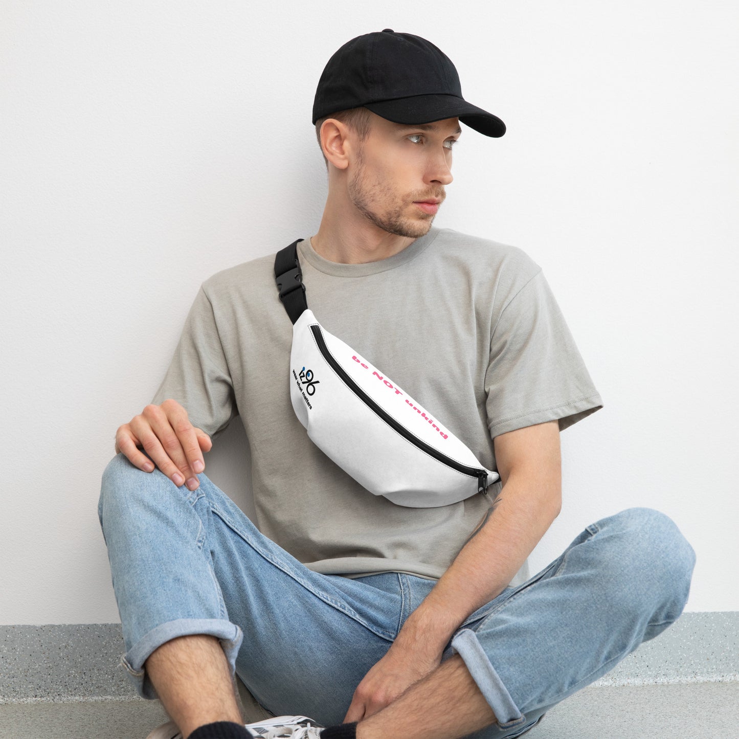Man sitting with a white waist bag featuring colorful logos on a light gray background