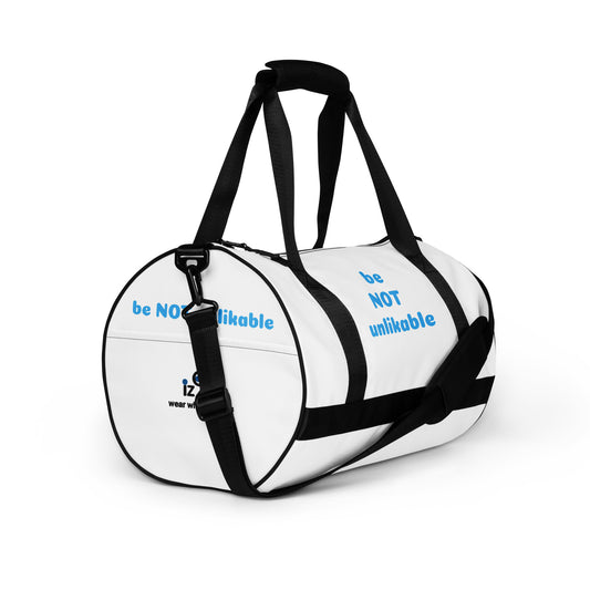 White duffel bag with black straps with 'be not unlikable' text on a white background