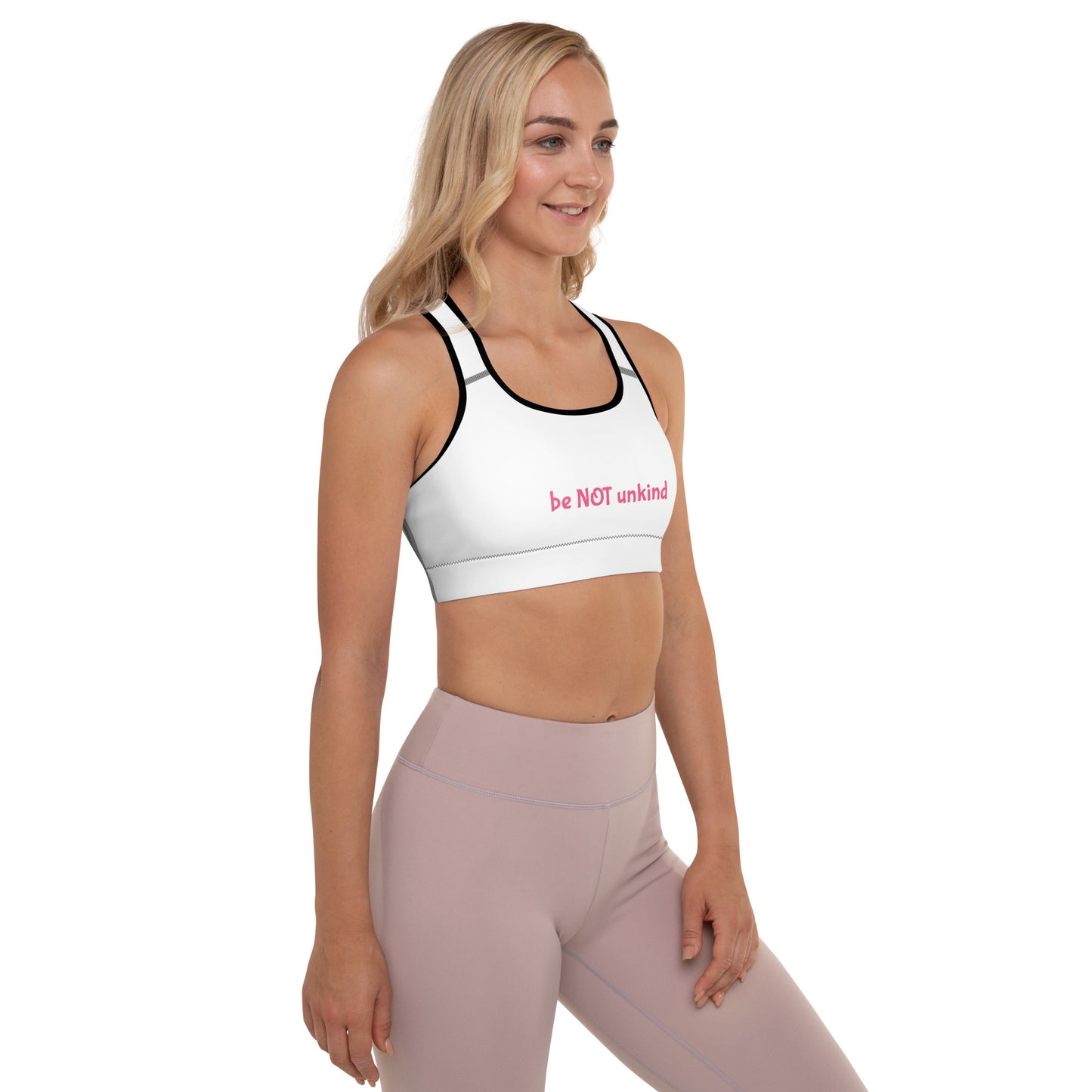 Woman wearing a white with black sports bra and pink leggings on a white background