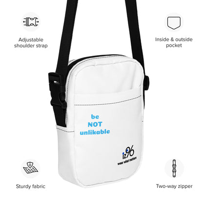 White bag with 'be NOT unlikable' text and brand logo, featuring adjustable strap and pockets.