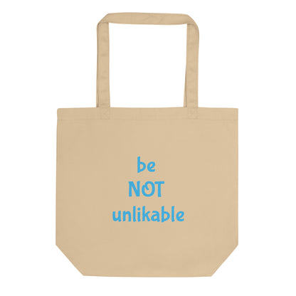 Beige tote bag with 'be NOT unlikable' text in blue on a white background