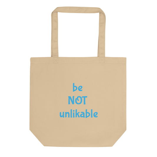 Beige tote bag with 'be NOT unlikable' text in blue on a white background
