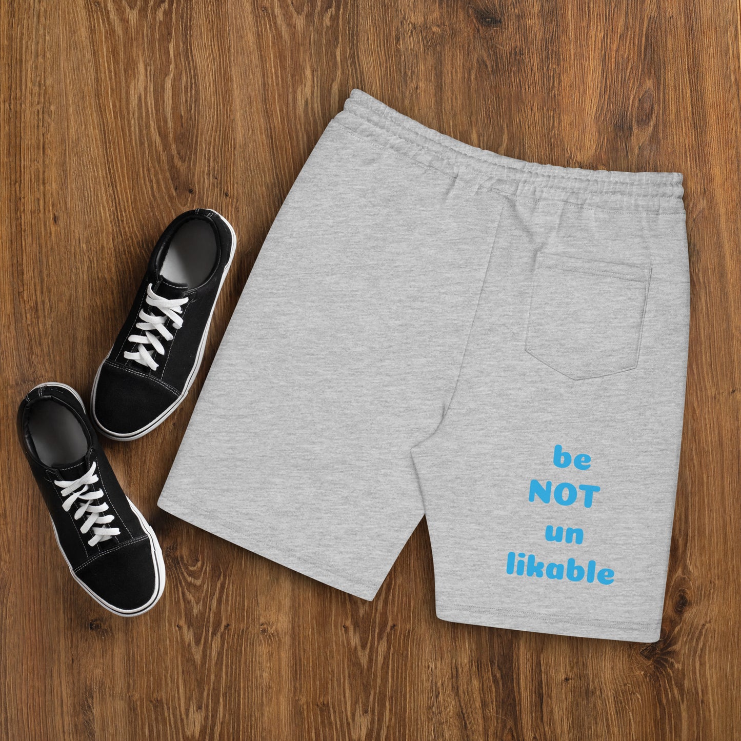 Gray shorts with text and black sneakers on a wooden surface