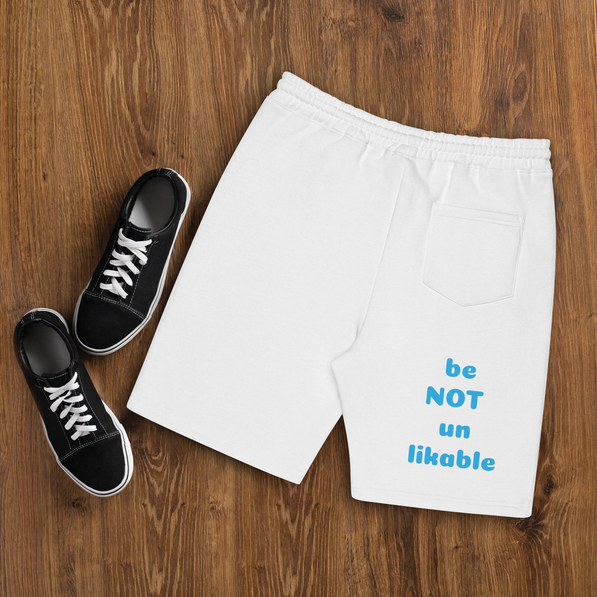 White shorts with text and black sneakers on a wooden surface