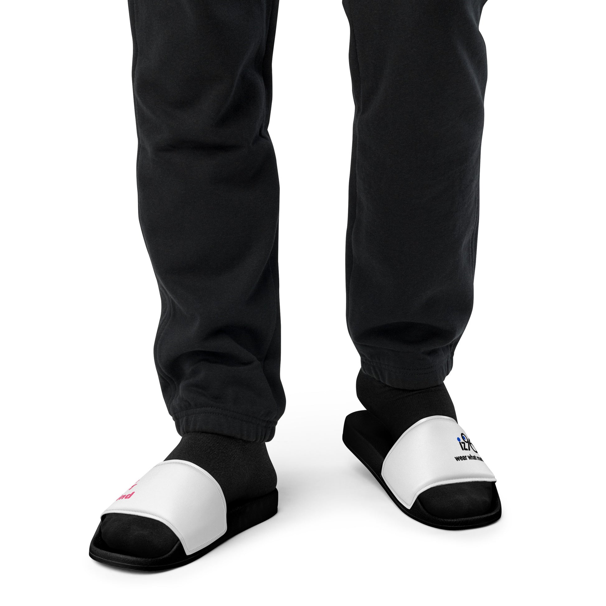Black and white slippers with text and logo design worn by a person in black pants on a white background