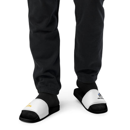 Black and white slippers with text and logo design worn by a person in black pants on a white background
