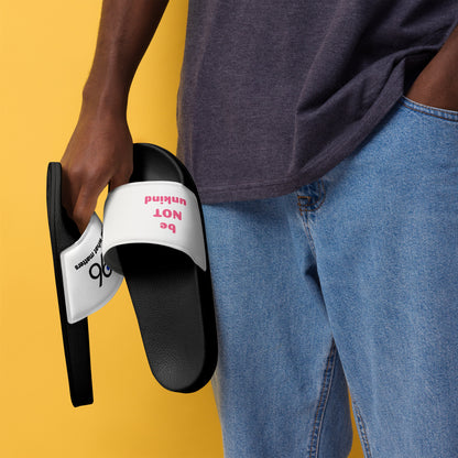 Person holding a black slide sandal with white sole against a yellow background