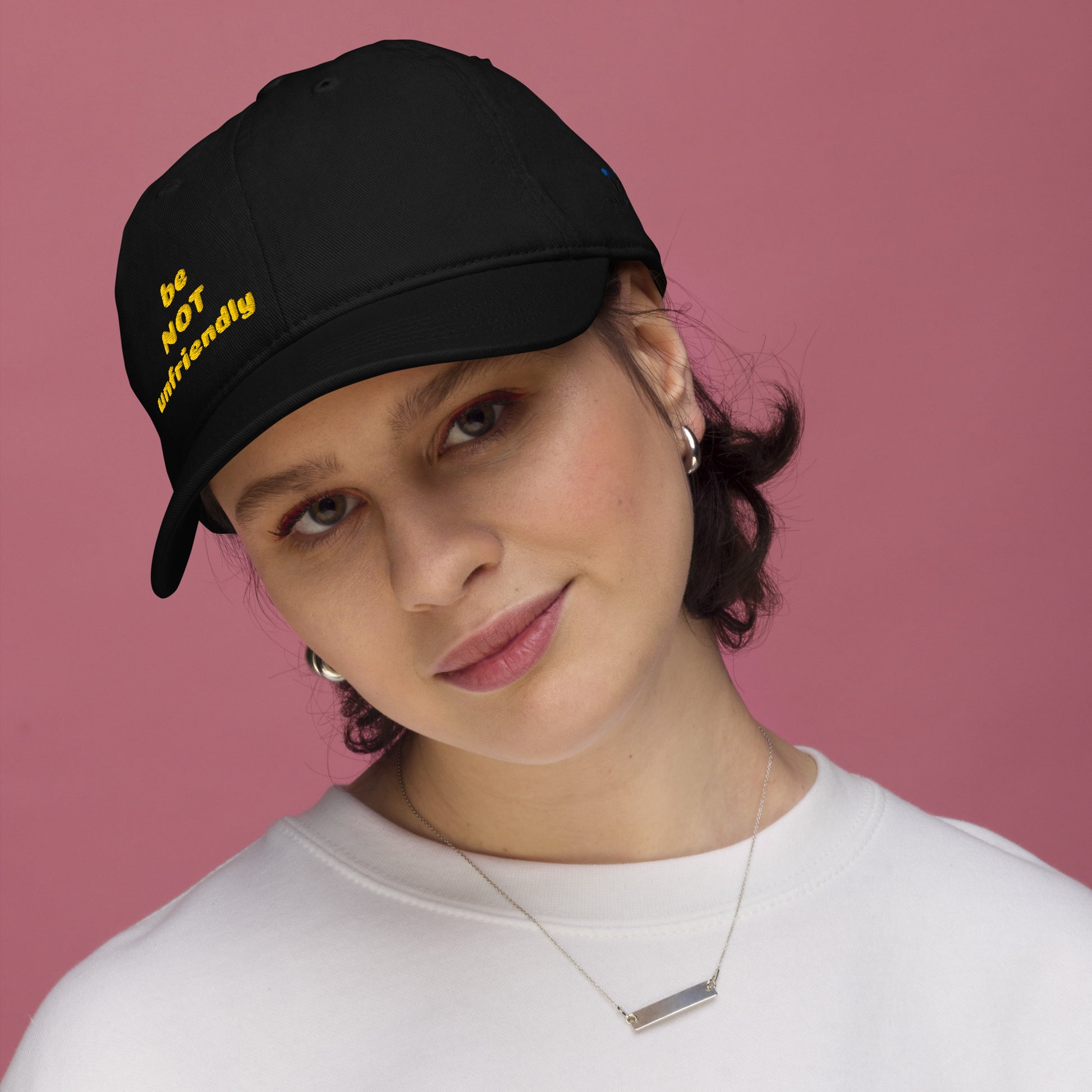 Person wearing a black cap with yellow text against a pink background