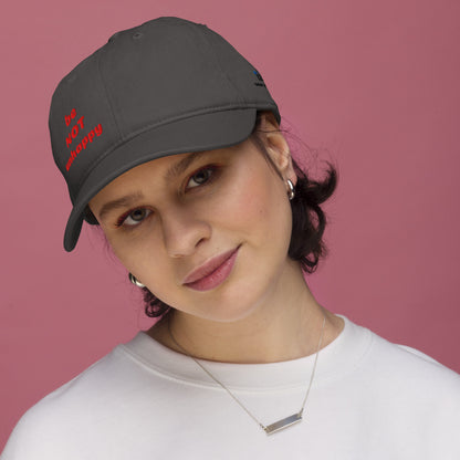 Person wearing a cap with 'be not unhappy' text on a pink background