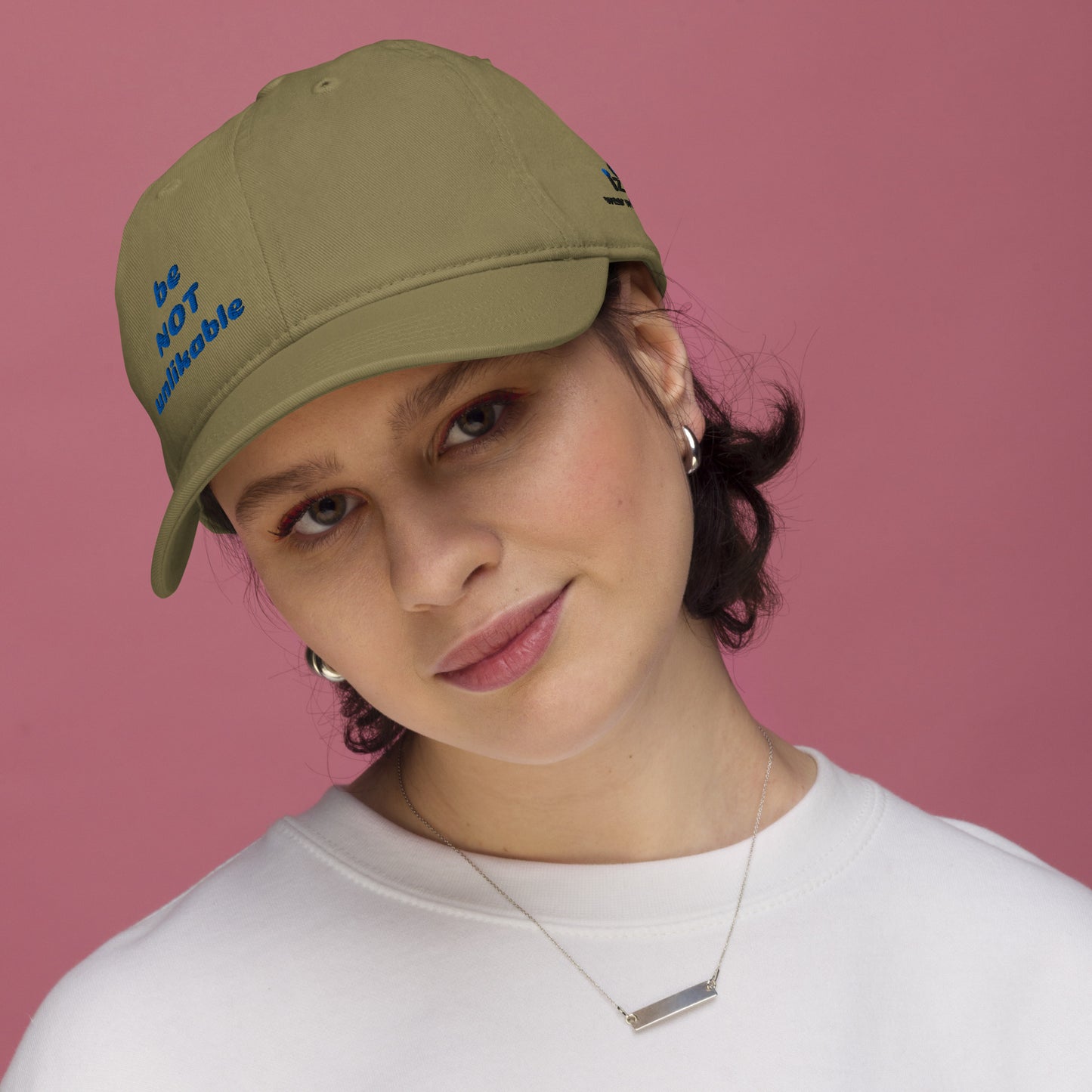 Woman wearing a green cap with text against a pink background