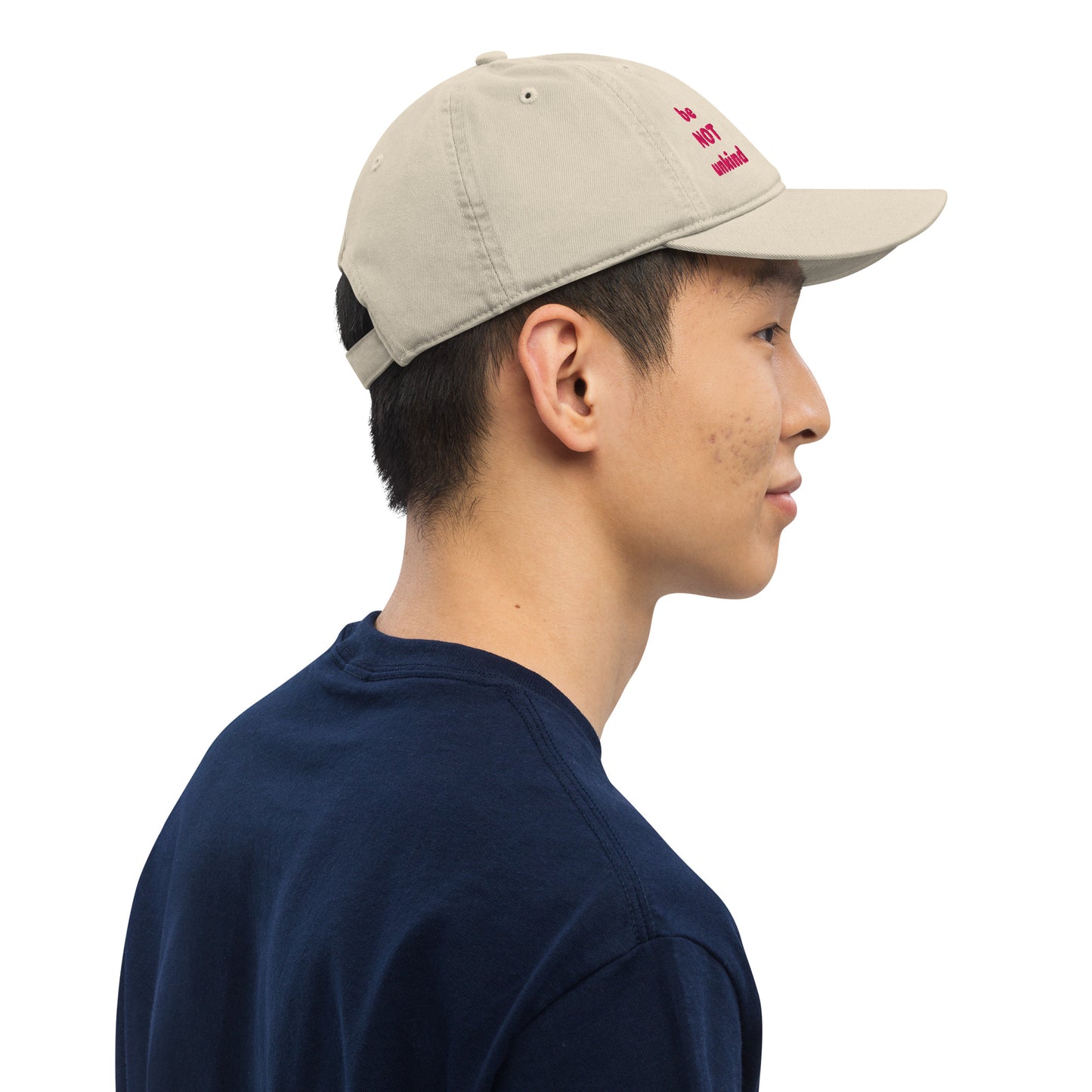 Person wearing a beige cap and navy shirt on a white background