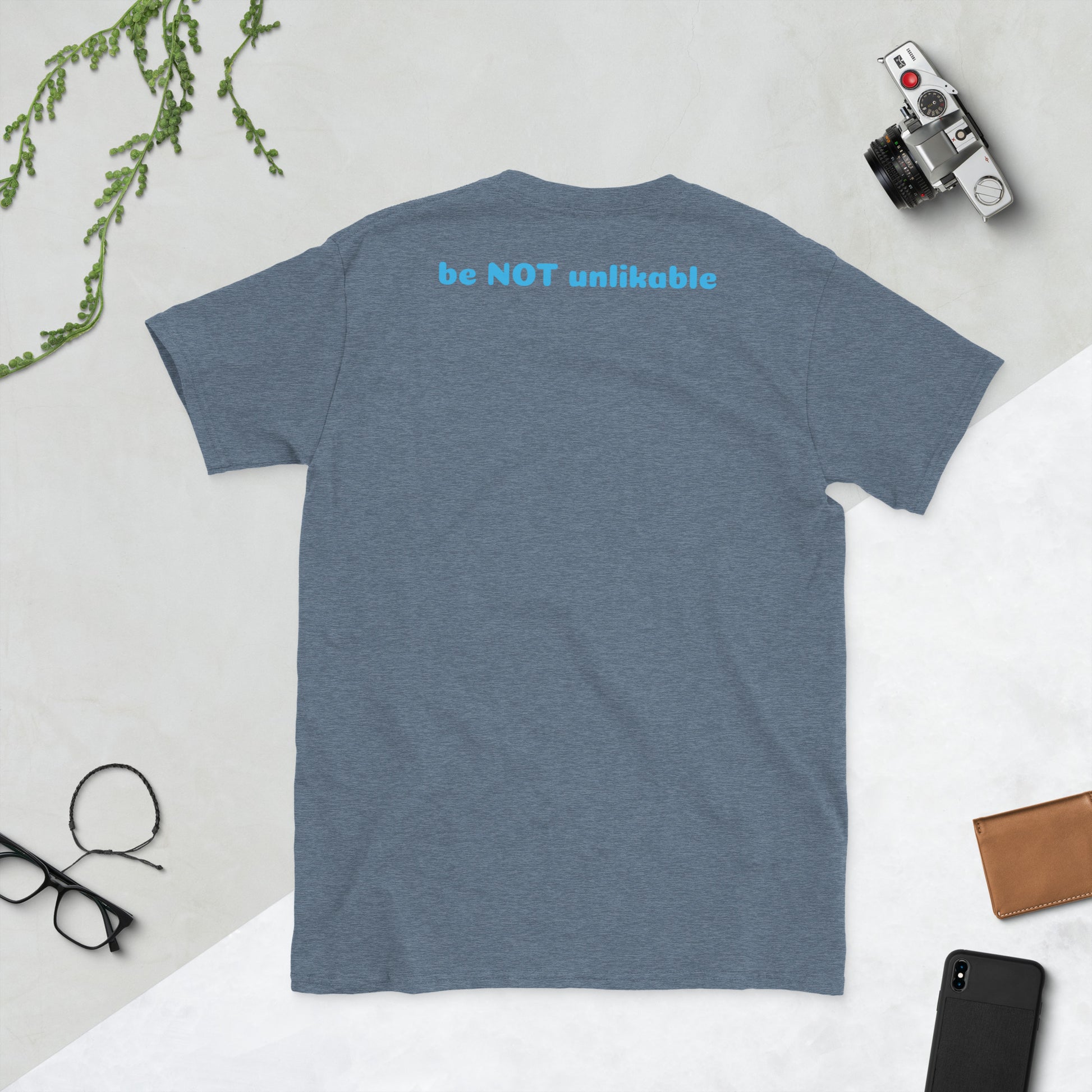 indigo t-shirt on a light gray surface with a camera, phone, and glasses.
