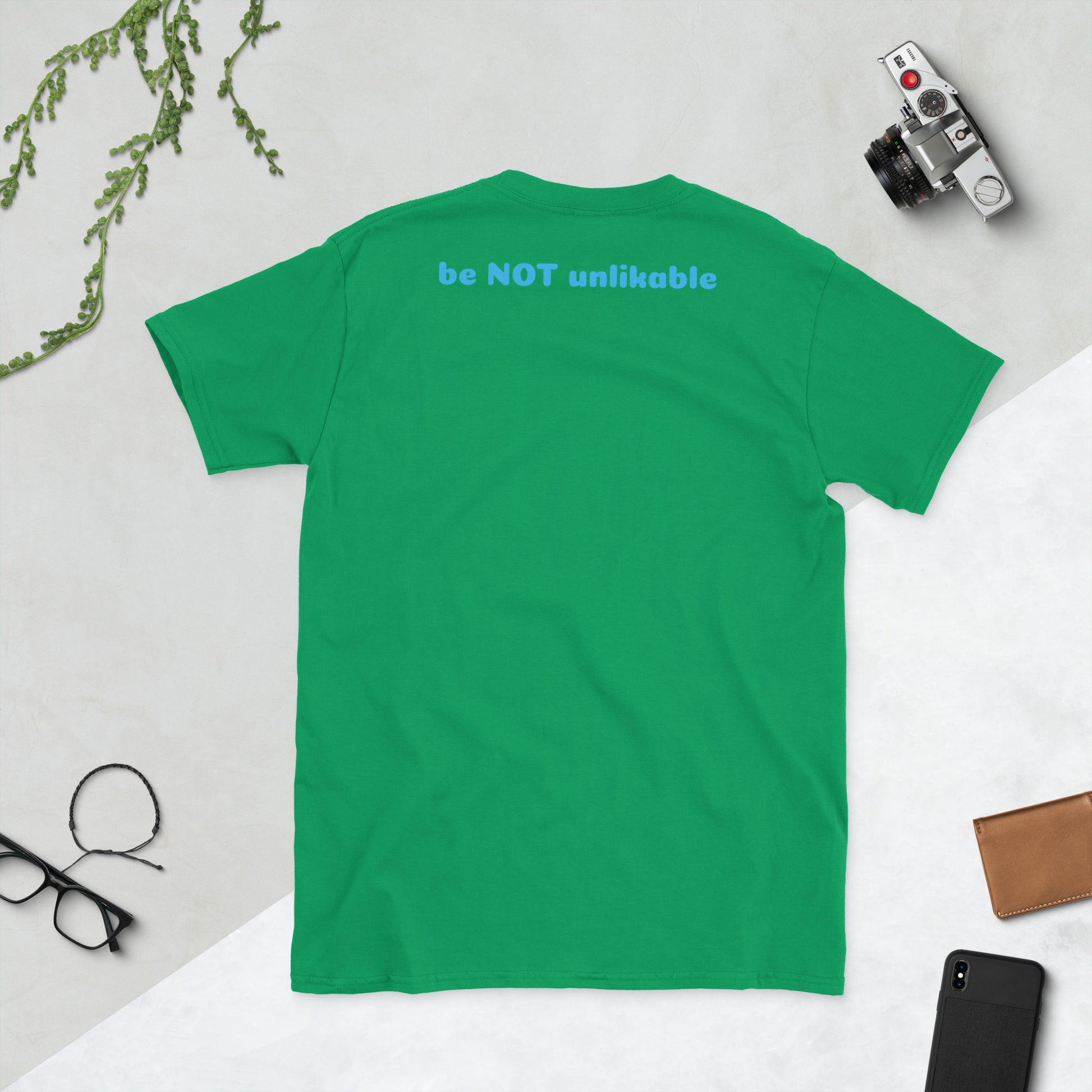 Irish green t-shirt with 'be NOT unlikable' text on a light gray background