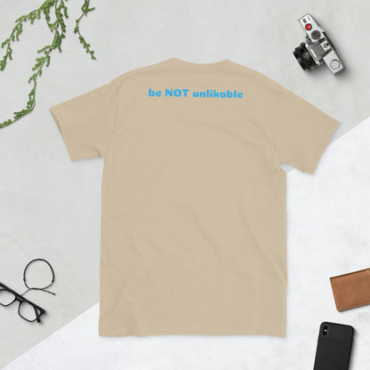 sand t-shirt with 'be NOT unlikable' text on a light gray background with accessories