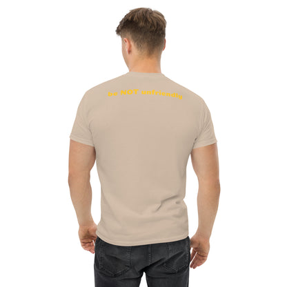 Man wearing a beige t-shirt with text on the back, standing against a white background