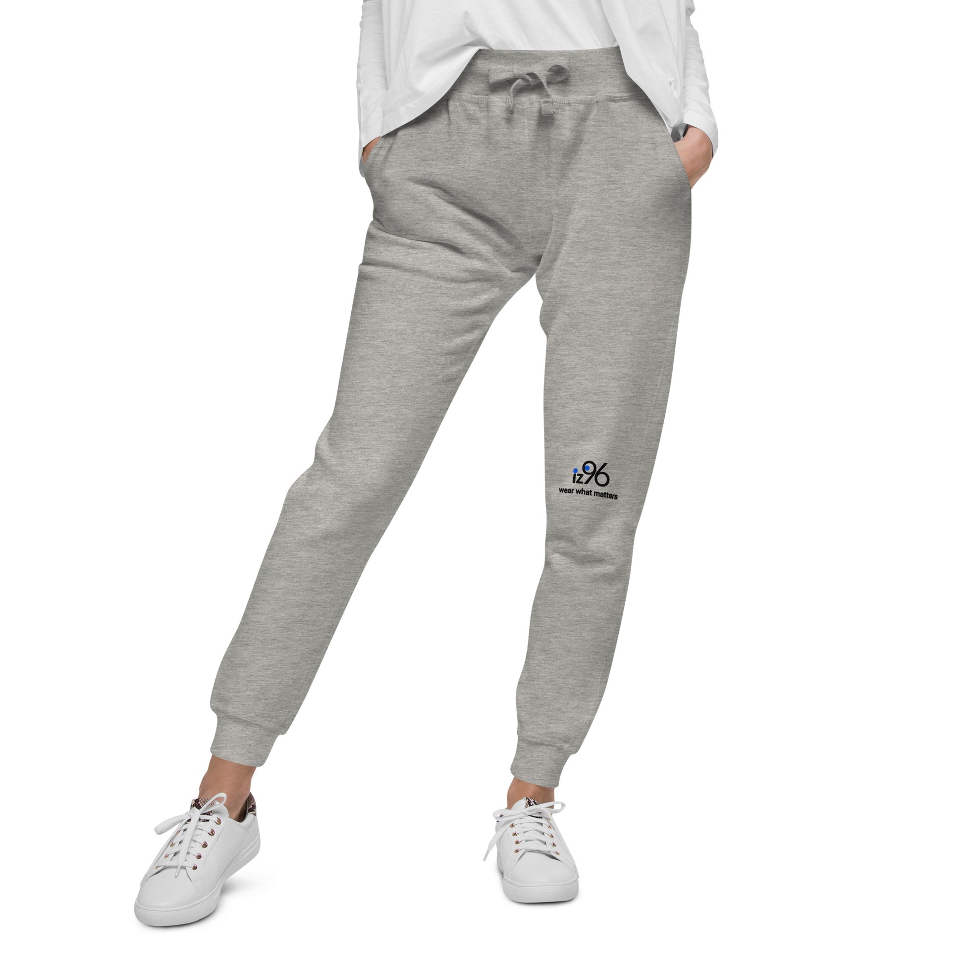 Person wearing gray sweatpants with logo and white sneakers on a white background