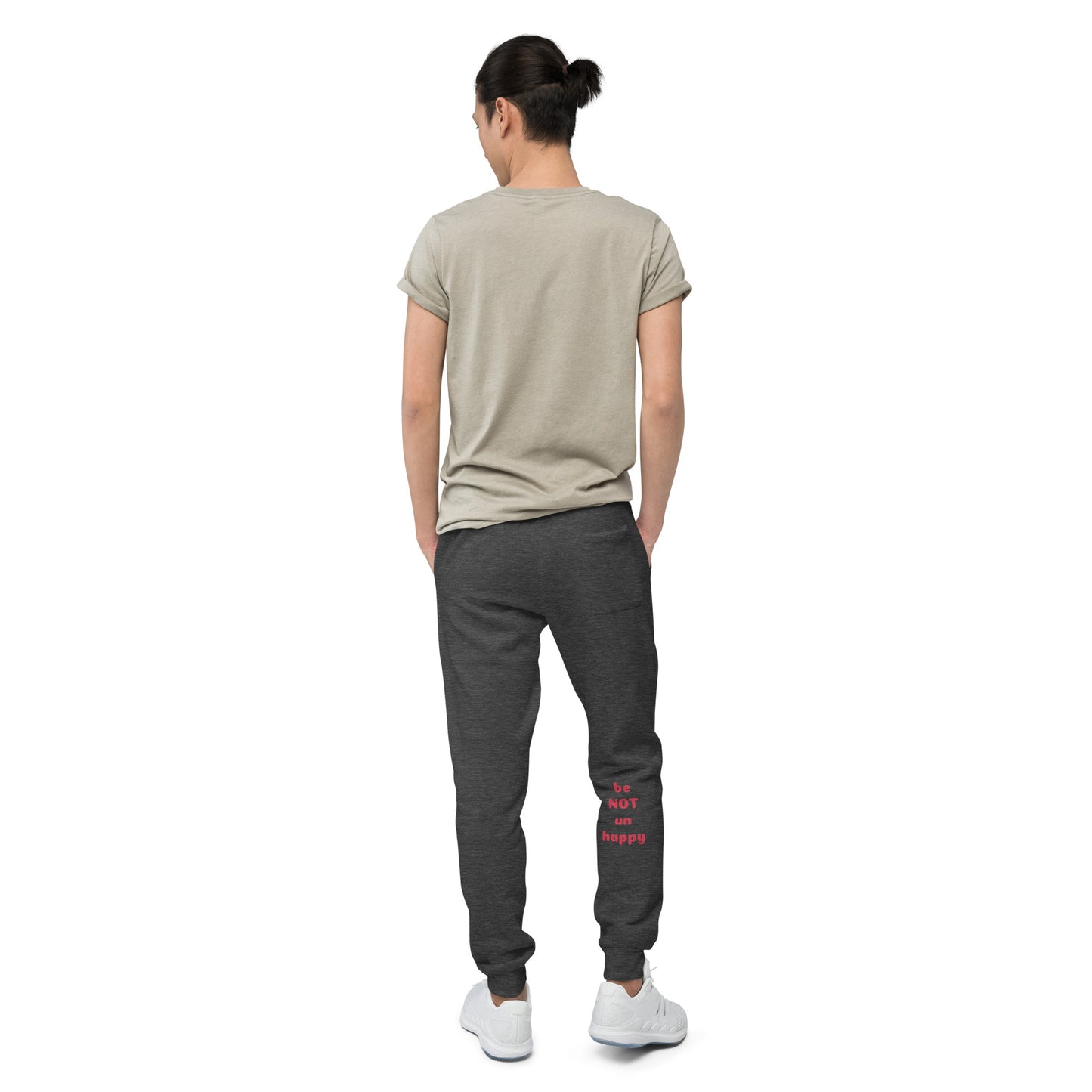 Person wearing a beige t-shirt and dark gray jogger pants with text on the back, standing against a white background.