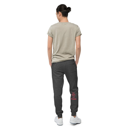 Person wearing a beige t-shirt and dark gray jogger pants with text on the back, standing against a white background.