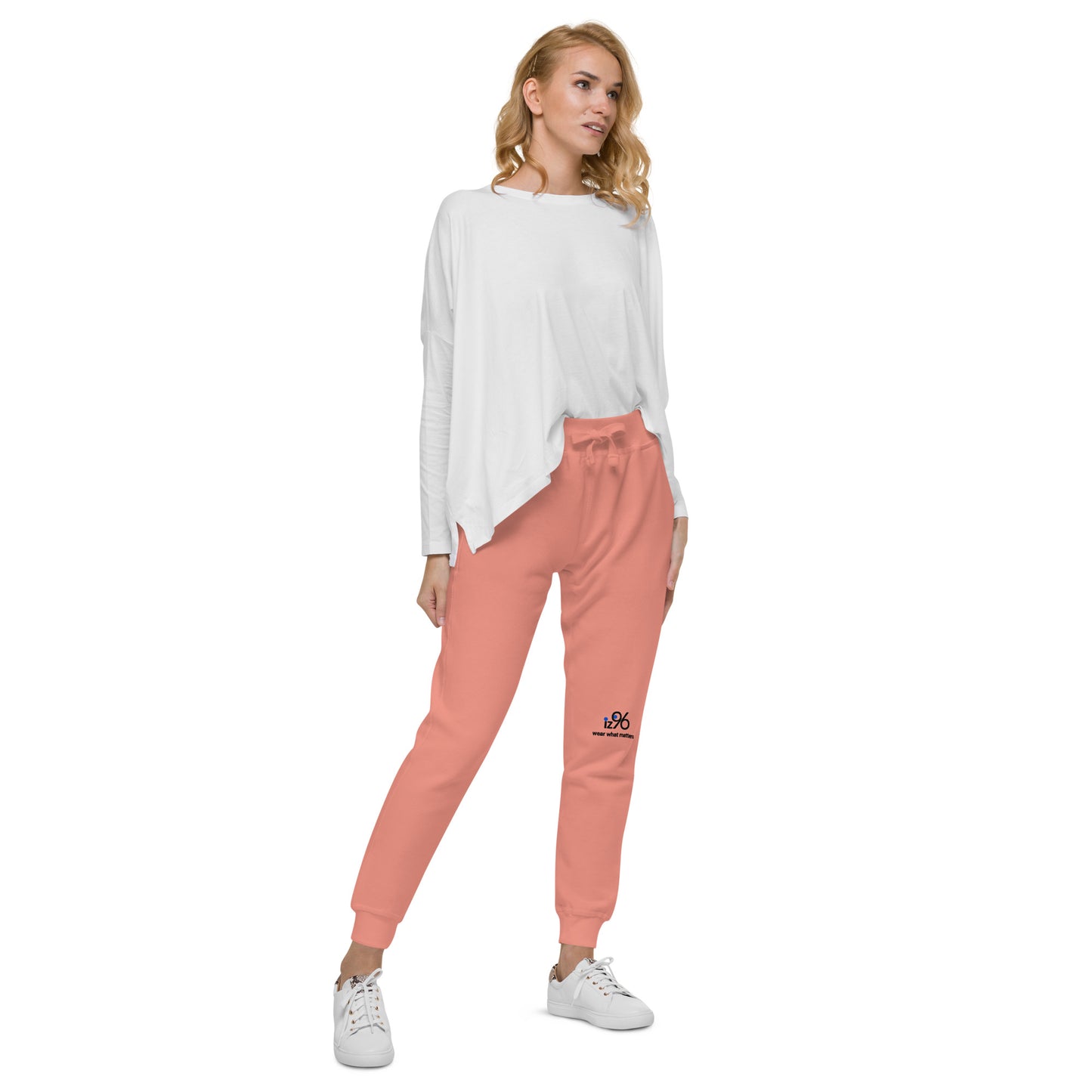 Woman wearing a white long-sleeve top and pink sweatpants on a white background