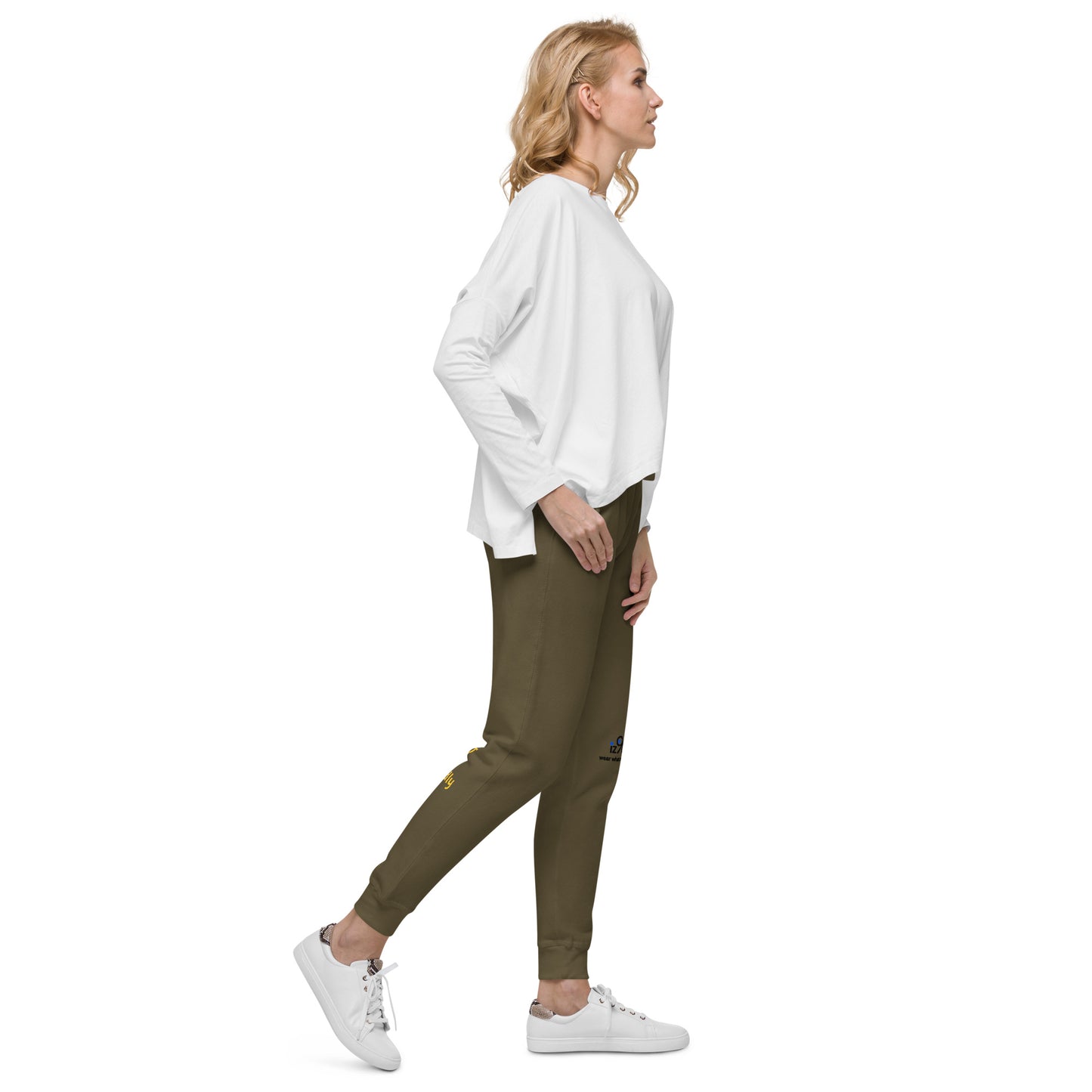 Woman wearing a white oversized sweater and military green jogger pants on a white background