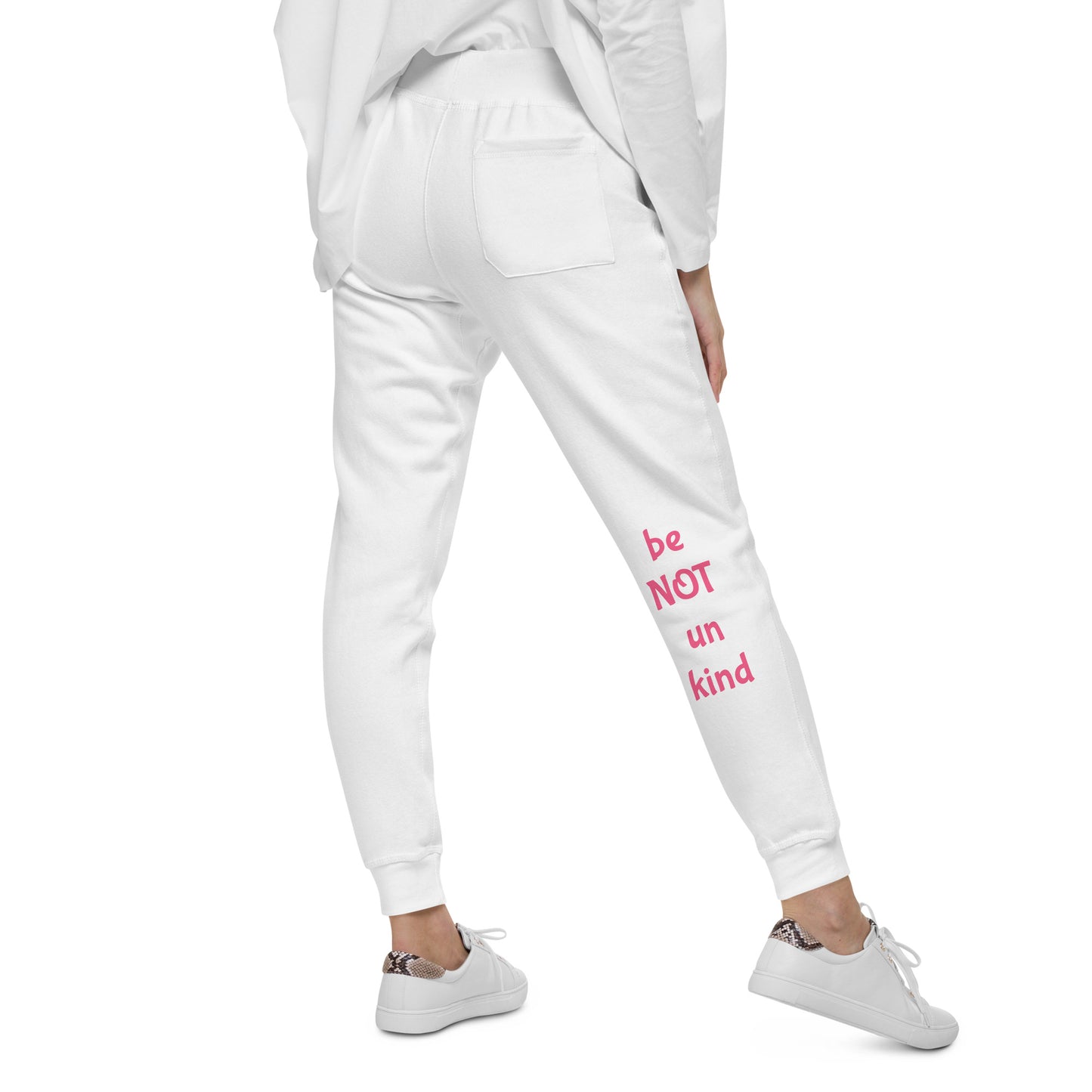 Person wearing white sweatpants with pink print and white sneakers on a white background