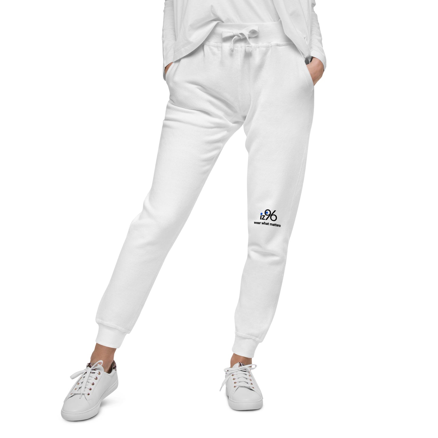 Person wearing white sweatpants with logo and white sneakers on a white background