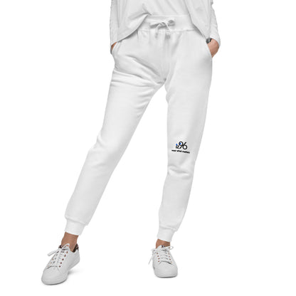 Person wearing white sweatpants with logo and white sneakers on a white background