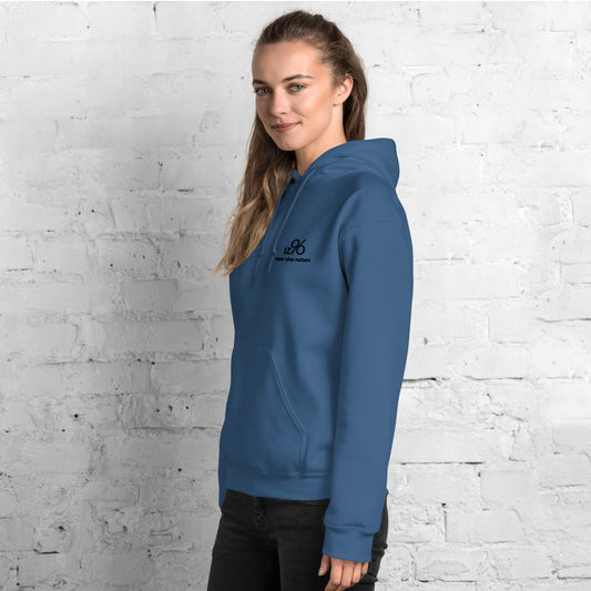 Person wearing a blue hoodie with a logo on a white brick wall background