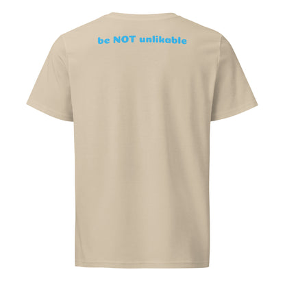 Beige t-shirt with 'be NOT unlikable' text on the back against a white background
