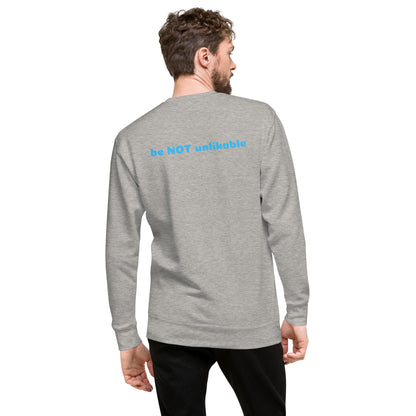 Man wearing a gray long-sleeve shirt with 'be NOT unlikable' text on the back, standing against a white background.