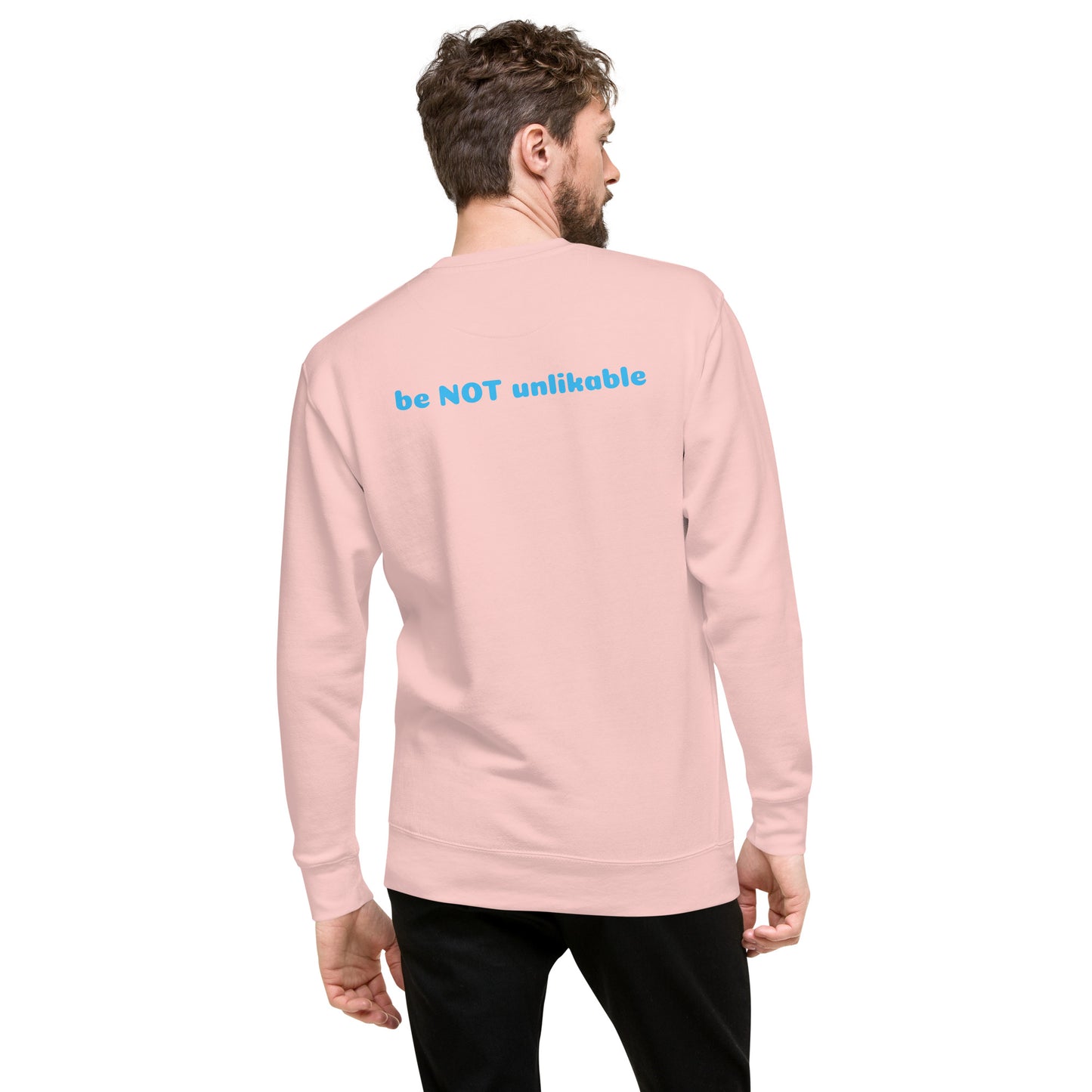 Person wearing a light pink long-sleeve shirt with 'be NOT unlikable' text on the back.