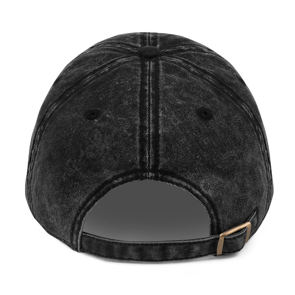 Black denim cap with a brown leather strap on a white background