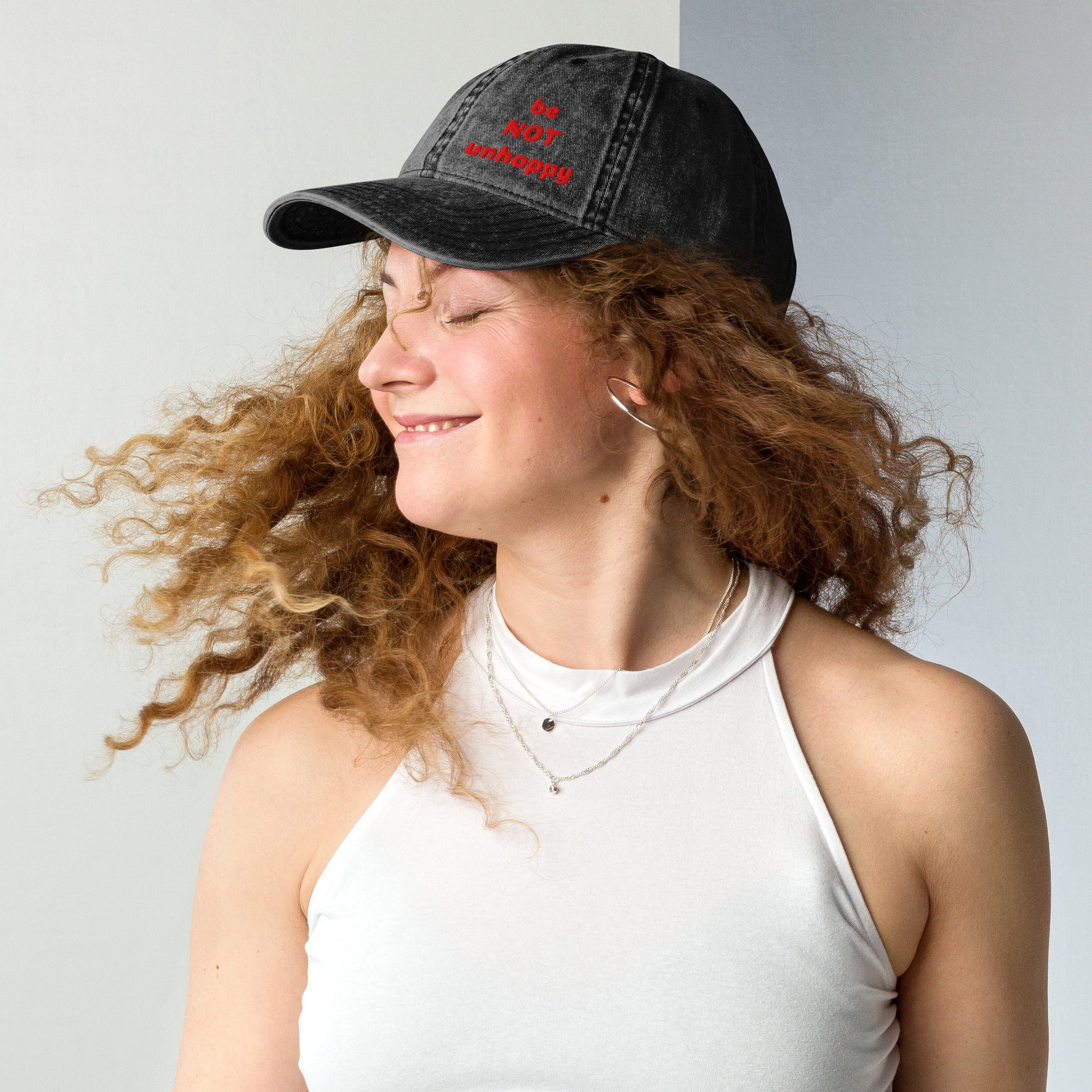 Woman wearing a black cap with a red logo against a plain background
