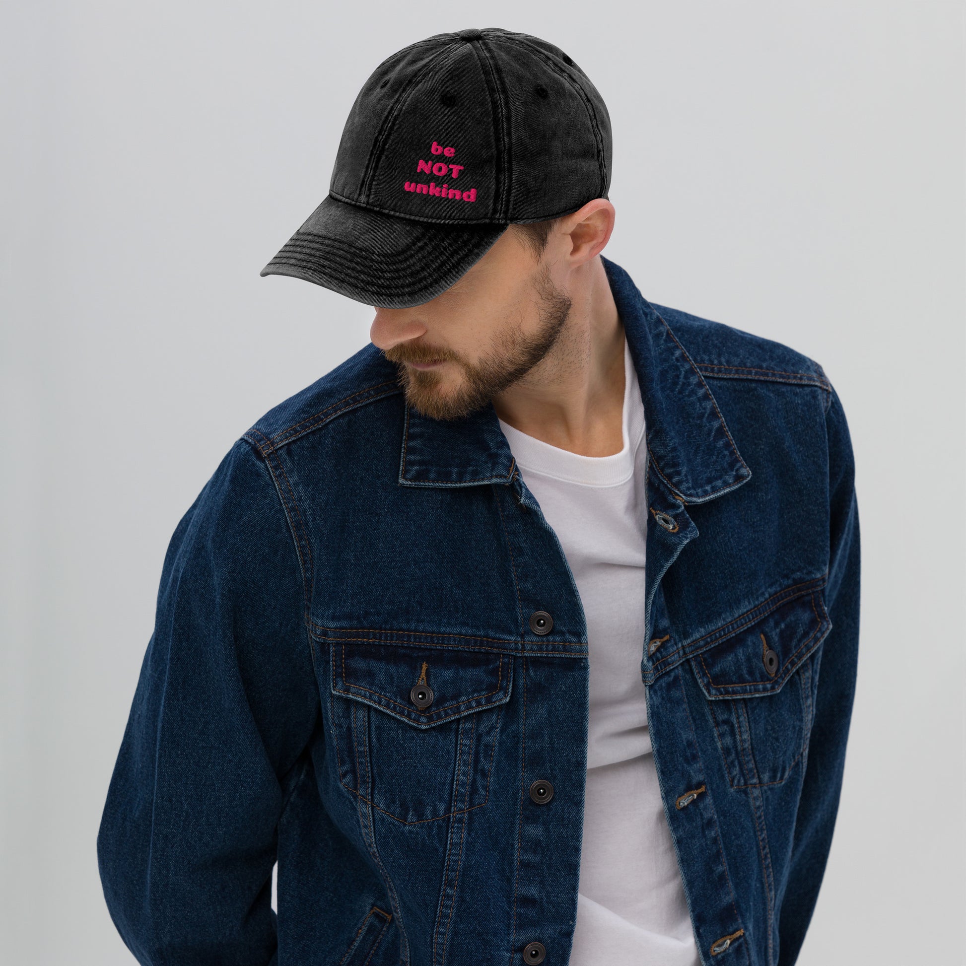 Man wearing a black cap and blue denim jacket on a gray background