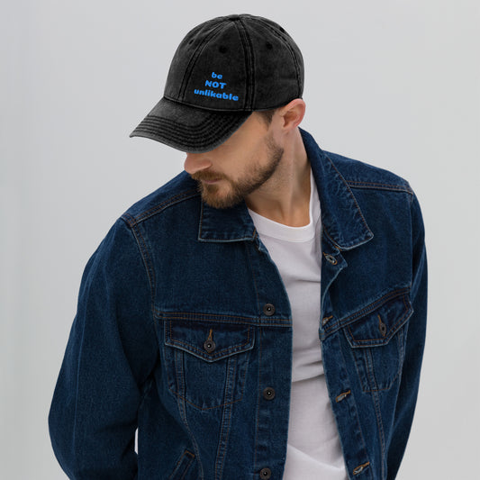 Man wearing a black cap and blue denim jacket on a gray background