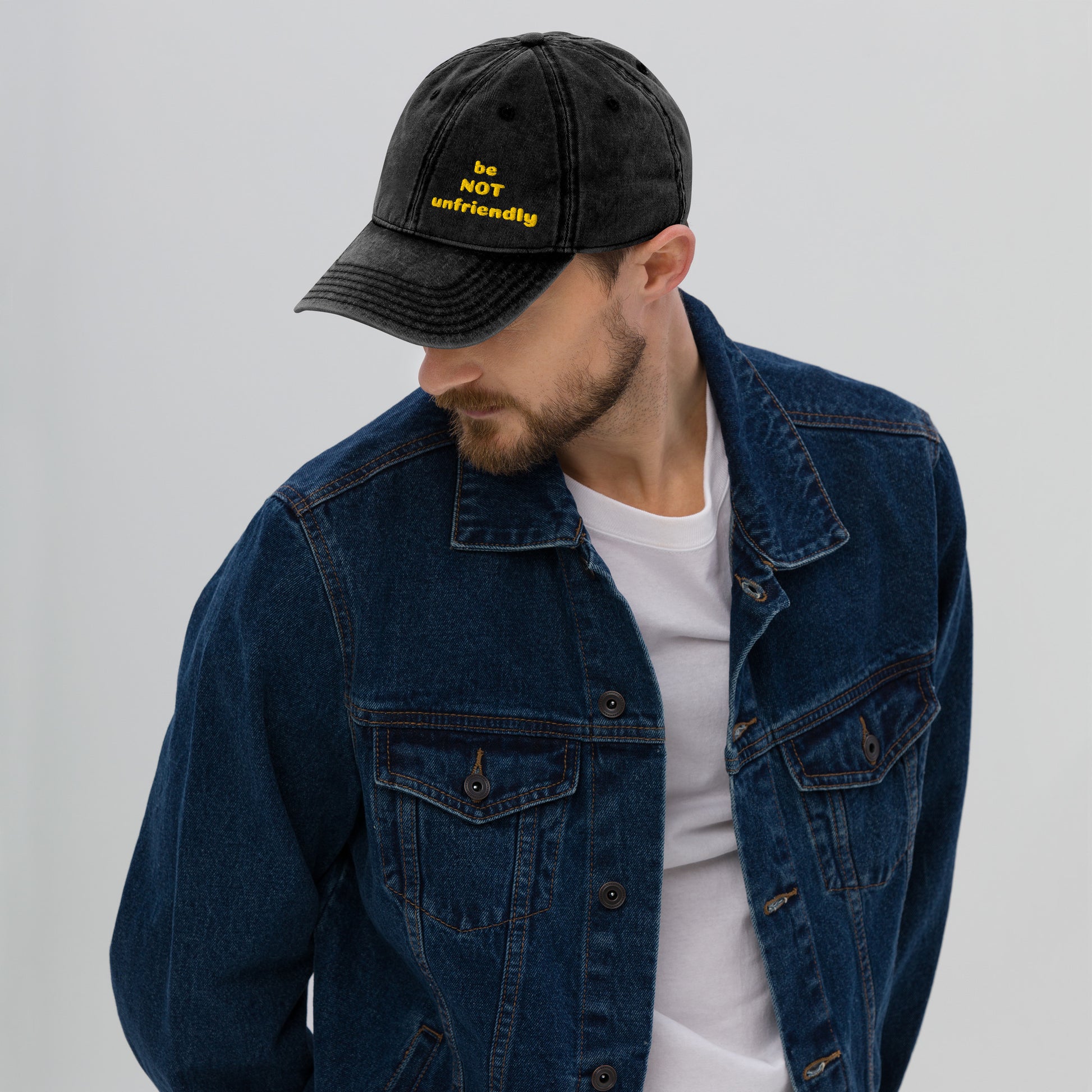 Man wearing a black cap and blue denim jacket on a gray background