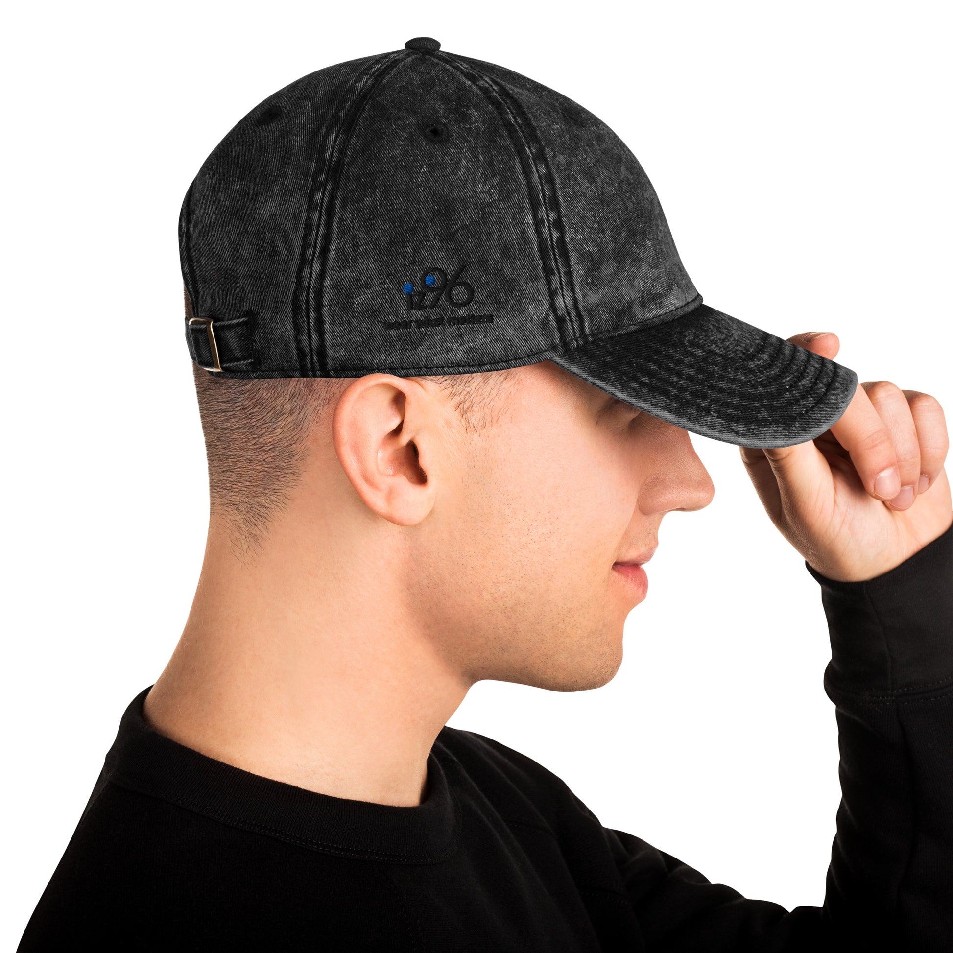 Person wearing a black denim cap with a blue patch on a white background