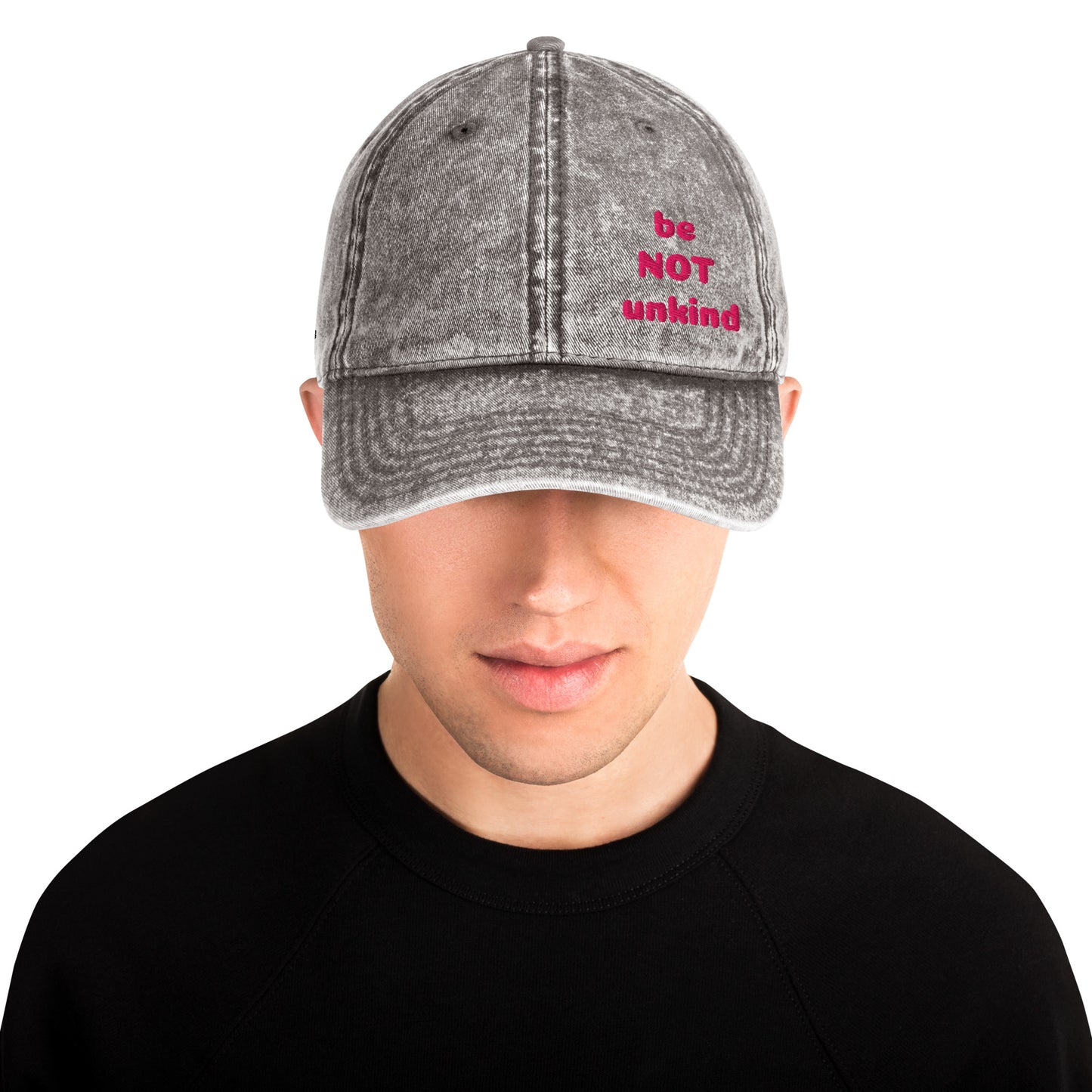 Person wearing a gray denim cap with pink text on a white background