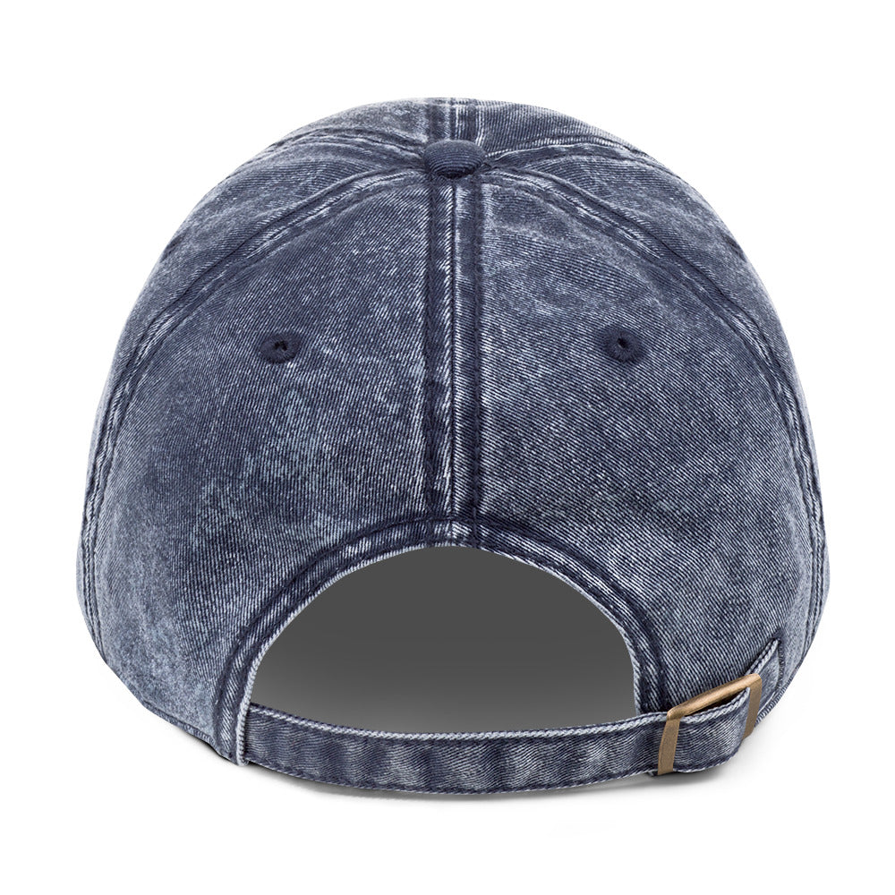 Blue denim cap with a brown strap on a white background