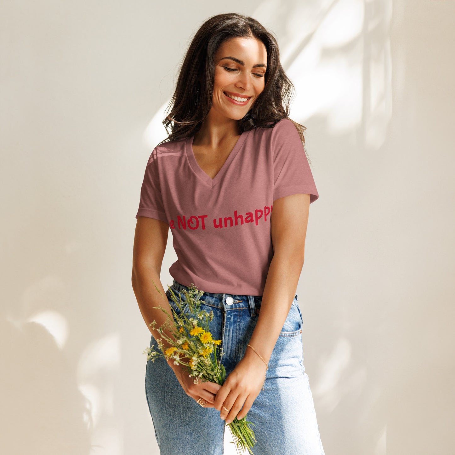 Woman wearing a mauve V-neck t-shirt holding flowers against a white background