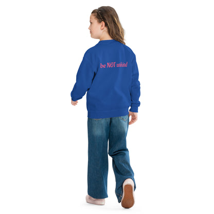 Person wearing a blue sweatshirt with 'be NOT unkind' text on the back, standing against a white background