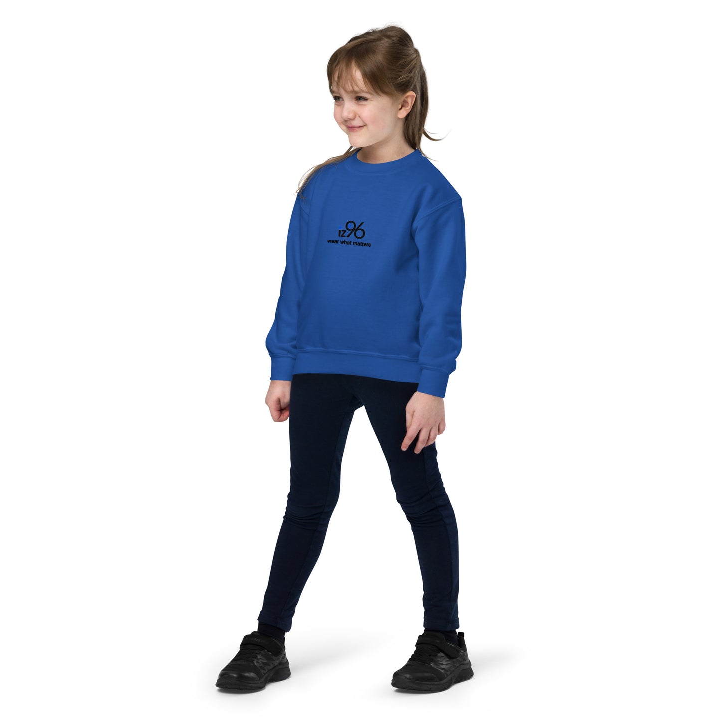 Young girl wearing a blue sweatshirt and black pants on a white background