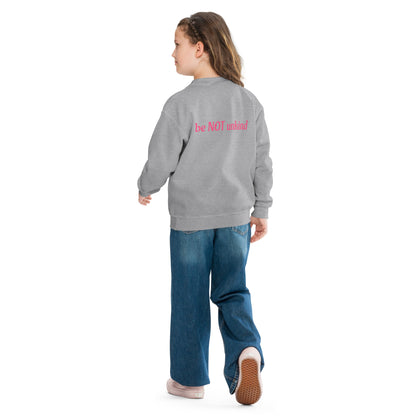 Child wearing a gray sweatshirt and blue jeans on a white background